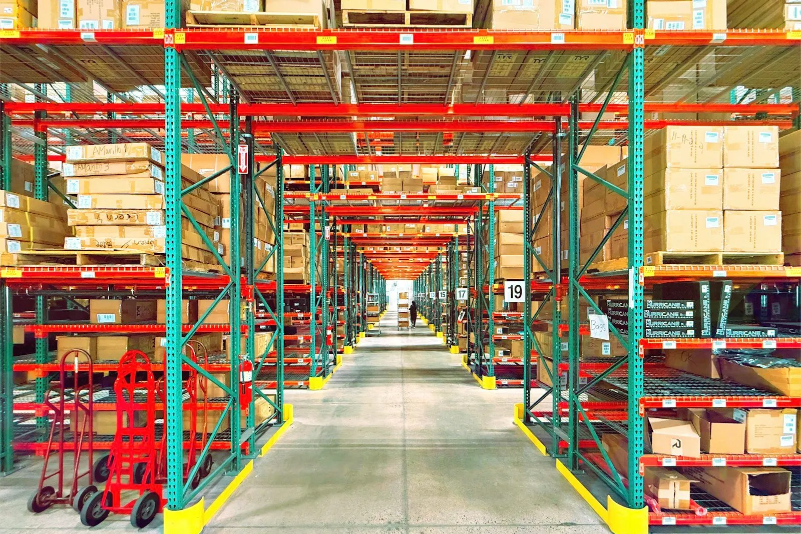 Interior de un almacén con estanterías y mercadería paletizada